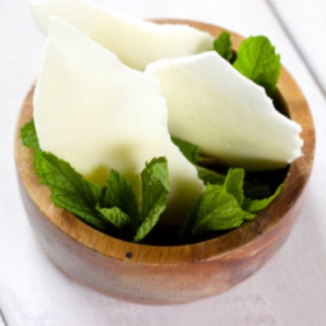 Shards of Apple Mojito Meringue made using Special Ingredients Easy Whip and Mint Flavouring Oil, set in a wooden bowl with mint leaves on a kitchen table. 
